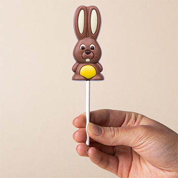 Gelber Schokoladenhase zu Ostern, in der Hand präsentiert