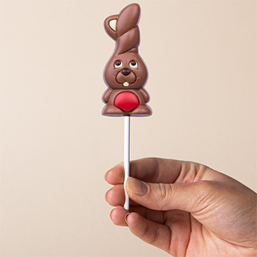 Roter Schokoladenhase zu Ostern in der Hand präsentiert