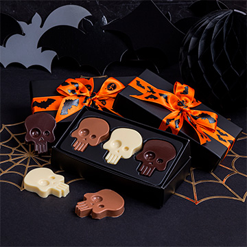 Drei Schokoladen-Halloween-Totenköpfe in einem dekorativen Arrangement