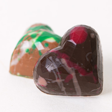 Herzförmige Pralinen in einer dekorativen grauen Schachtel, präsentiert in Ihrer Handfläche