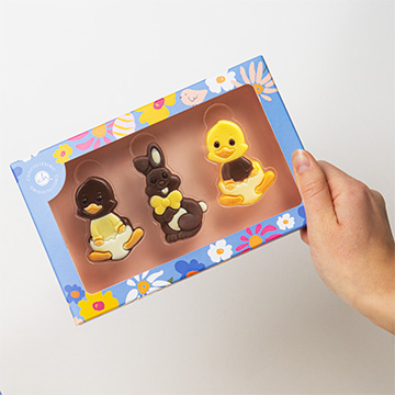 Österliches Figuren-Set aus belgischer Schokolade mit Hasen und Küken – in der Hand präsentiert