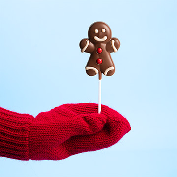 Ein Lebkuchenmann in Form eines Lutschers in der Hand präsentiert