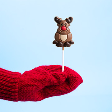 Ein Rentier in Form eines Lutschers in der Hand präsentiert