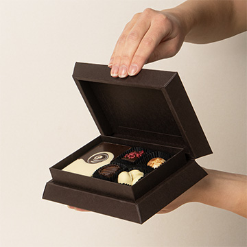 ein Set Pralinen aus belgischer Schokolade in den H&auml;nden pr&auml;sentiert