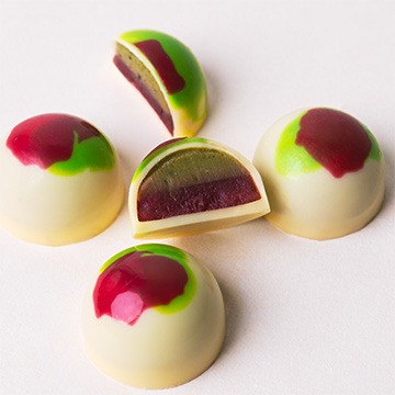 Handgefertigte Pralinen aus weißer belgischer Schokolade mit Matcha-Himbeer-Füllung