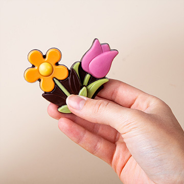 G&auml;nsebl&uuml;mchen und Tulpen aus Schokolade in den H&auml;nden